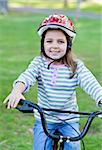 Joyful little girl riding a bike in a park