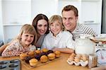 Happy family presenting their muffins in the kitchen