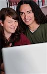 Interracial couple with a laptop at a coffee house with copy space