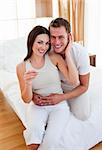 Enamoured couple finding out results of a pregnancy test sitting on bed