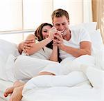Lively couple finding out results of a pregnancy test sitting on bed