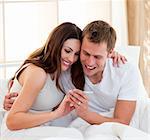 Joyful couple finding out results of a pregnancy test sitting on bed