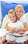 Blond brother and daughter reading books sitting on bed