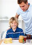 Blond little boy and his father preparing breakfast  in the kitchen