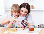 Adorable little girl and her mother preparing toasts in the kitchen