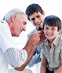 Senior doctor examining a little boy's ears at the practice