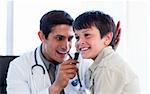 Smiling doctor examining little boy's ears at the practice