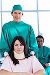 Attractive surgeon carrying a patient on a wheelchair in a hospital