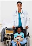 Young male doctor and Smiling girl on a wheelchair with thumb up in the hospital