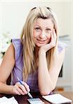 Portrait of a cheerful woman paying her bills in a living-room