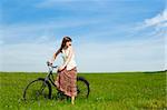 Young woman with a vintage bicycle on a green meadow