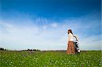 Happy young woman with a vintage bicycle on a green meadow