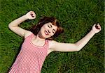 Top view of a beautiful young woman lying on a green meadow