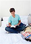 Teenager reading a book from school in his bedroom