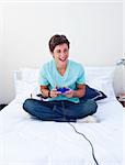 Excited teenager playing video games on his bed