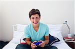 Attractive happy teenager playing video games in his bedroom