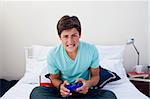 Excited teenager playing video games in his bedroom