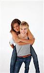 Teen guy giving a friend piggyback ride against white background