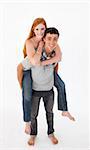 Young boy giving his girlfriend piggyback ride against white background