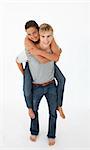 Young boy giving his girlfriend piggyback ride against white background