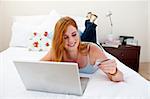 Young girl using a laptop and buying online in her bedroom