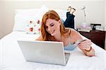 Young girl using a laptop and shopping online in her bedroom