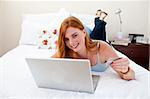 Teen girl using a laptop and shopping online in her bedroom