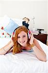 Smiling teenage girl listening to the music on the bed