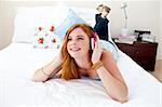 Beautiful teenager listening to the music on the bed