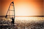 windsurfer silhouette against a sunset background