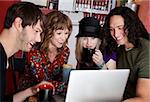 Four friends laughing at content on a laptop