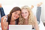 Portrait of smiling teen girls shopping online in a bedroom