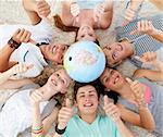 Teenagers on the floor with a terrestrial globe in the center of their heads and with thumbs up