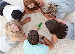 Group of teenagers lying on the floor and playing with a bottle