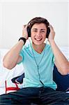 A teenage guy listening to the music in his bedroom with headphones