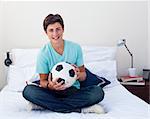 Teen guy holding a soccer ball in his bedroom