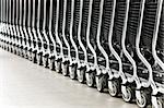 row of empty shopping carts in the big supermarket (extremely shallow depth of field, focus on fourth wheel from right)