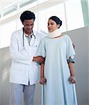 Physical therapist helping a woman on crutches in a hospital