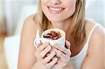 Close-up of a cheerful woman drinking a coffee sitting on a sofa