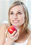 Beautiful woman eating an apple at home