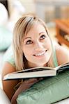 Attractive woman lying on a sofa reading a book at home