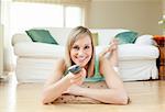 Young woman watching TV lying on the floor at home