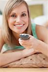 Smiling blond woman watching TV lying on the floor at home