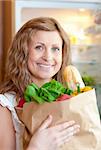 Radiant woman holding a grocery bag in the kitchen