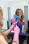 Smiling woman cleaning bathroom's mirror at home