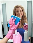 Cheerful woman cleaning bathroom's mirror at home
