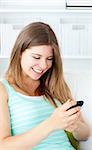 Laughing young woman writing a text message with her mobile phone