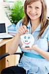 Attractive woman saving money in a piggy-bank in the office