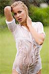 young sexy blond woman otodoor in a garden playing with water and rain with wet dress