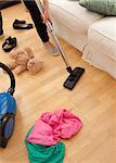 Blond young woman vacuuming the living-room at home
